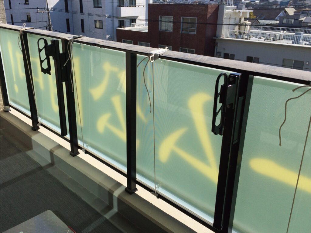 マンションのバルコニー手すりに横断幕がしっかりと設置されている様子。建物情報を掲出した広告幕のクローズアップ写真